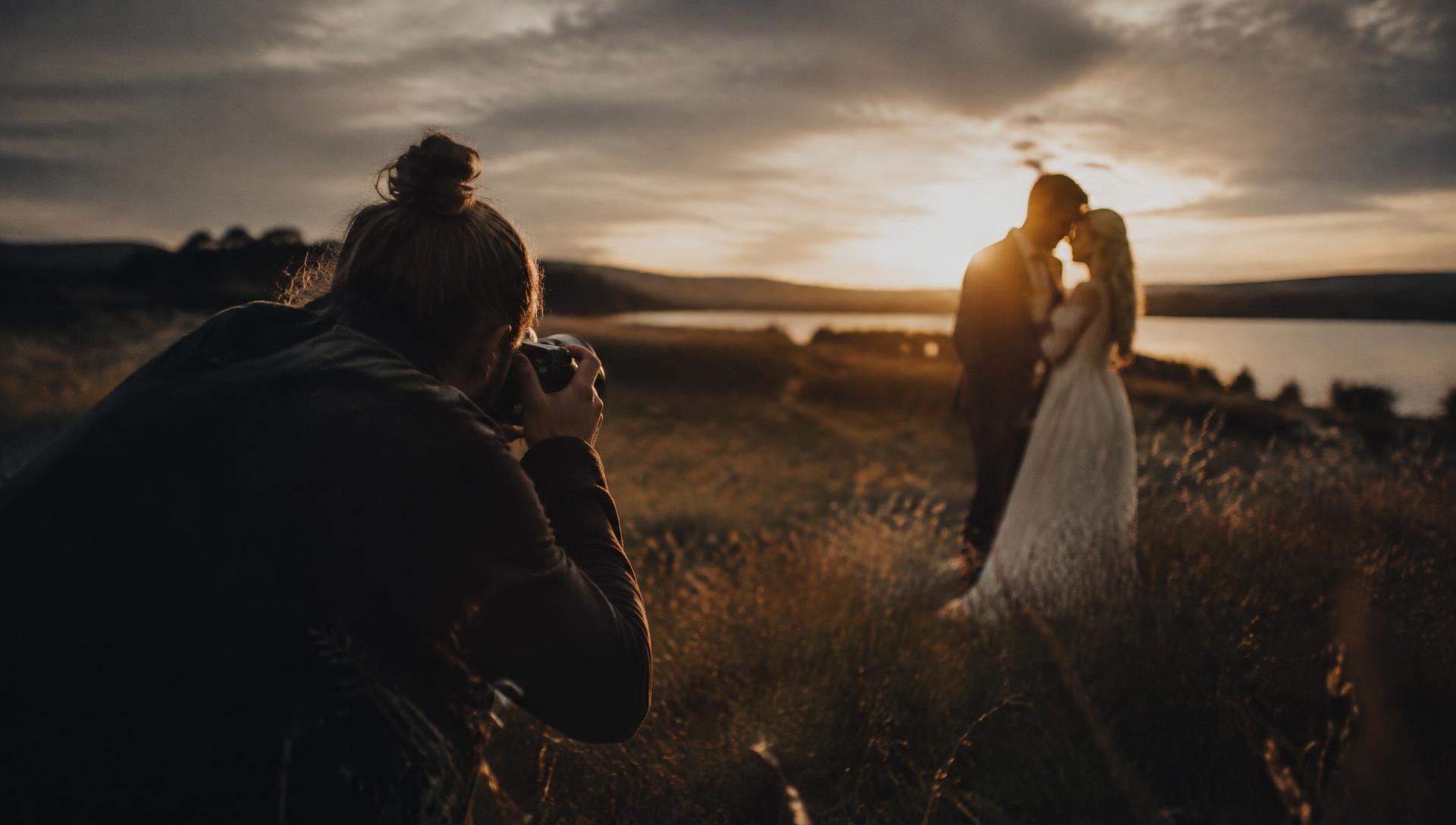 Bröllopsfotograf fotograferar ett brudpar i solnedgång